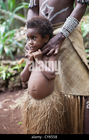 Pacifique Sud, Vanuatu, Port de l'IVL, Ekasup Village. Jeune garçon en costume traditionnel appuyé contre son père. Banque D'Images