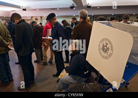 6 novembre 2012, Brooklyn, NY, US. Cabine de vote et des gens qui attendent en ligne au lieu de scrutin que les New-yorkais voter à l'élection présidentielle américaine de 2012. Banque D'Images