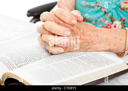 Gros plan du senior woman's hands on bible, plié dans la prière. Banque D'Images