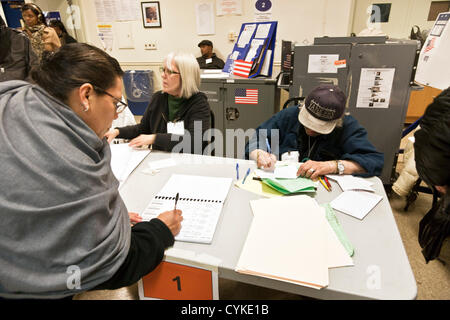 Les signes d'une femme pour son bulletin de papier dans un west side Manhattan high school, avant de passer à la vie privée pour le remplir à booth & scanner pour numériser ; New York, 6 novembre 2012, Banque D'Images