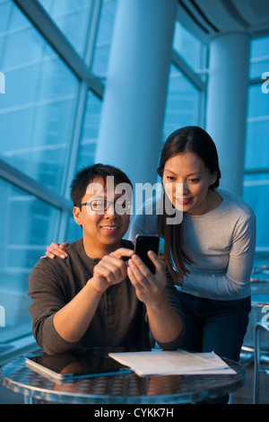 Asian couple looking at cell phone Banque D'Images