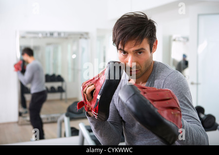 Formateur portant des gants rembourrés en salle de sport Banque D'Images