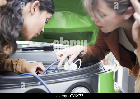 Les femmes de brancher en voiture électrique Banque D'Images