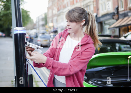 Voiture électrique de charge femme on street Banque D'Images