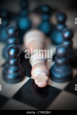 Les hommes d'échecs pions entourant fallen king Banque D'Images