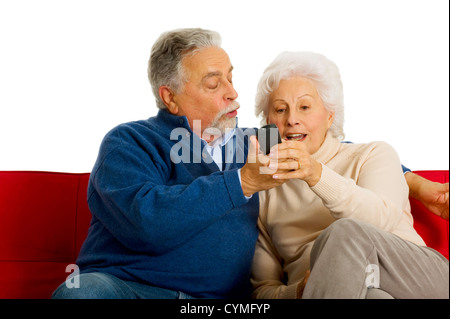 Couple de personnes âgées sur le canapé avec la télécommande du téléviseur Banque D'Images