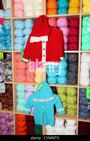 Vêtements de bébé tricotés et balles de laine sur des étagères Banque D'Images