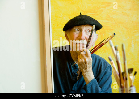 Peintre âgée portant un béret travaille sur une grande toile Banque D'Images