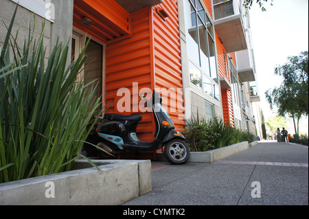 Scooter s'appuyant sur une porte d'un bloc d'appartements Banque D'Images