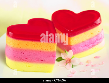 Péruvien colorés heart-shaped jelly au lait gâteaux appelés Torta Helada avec une fleur de la pêche sur la plaque Banque D'Images