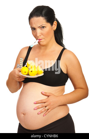 Triste femme enceinte avec le thermomètre ayant de la fièvre et être froid et citrons holding pills isolé sur fond blanc Banque D'Images