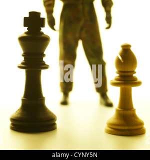 Conflit, opposant deux pièces des échecs et la figure de combat militaire en tenue de camouflage Banque D'Images