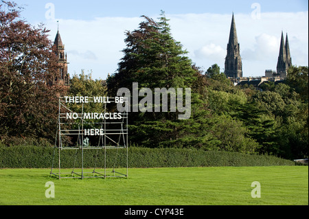 : Un "No miracles ici' dans les jardins de la Scottish National Gallery of Modern Art à Edimbourg, Ecosse avec trois clochers dans la ville derrière. C'est est une installation par l'artiste écossais Nathan Coley. Banque D'Images