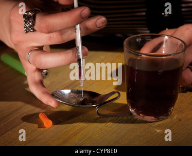 Gros plan du dessin à la main de femme black tar heroin dans une aiguille Banque D'Images