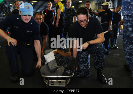 Les marins à bord de l'USS Dwight D. Eisenhower (CVN 69) se préparent à soulever une civière lors d'un exercice de grand nombre de victimes dans le hangar du navire. L'exercice fait partie de la formation sur l'état de préparation du navire afin d'assurer une intervention efficace en cas d'urgence pendant le déploiement. Banque D'Images