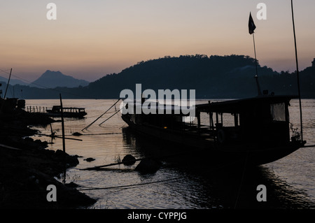 LUANG PRABANG, Laos — coucher de soleil sur le Mékong. Le fleuve Mékong coule près de la ville historique de Luang Prabang dans le nord du Laos. Le fleuve, l'une des principales voies navigables de l'Asie du Sud-est, joue un rôle crucial dans l'écologie, l'économie et la culture de la région. Luang Prabang, site classé au patrimoine mondial de l'UNESCO, est situé au confluent du Mékong et du Nam Khan. Banque D'Images