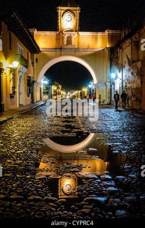 Santa Catalina Archway Rue pavée humide réflexion Antigua Guatemala // L'arche sur la rue du couvent de Santa Catalina dans le centre d'Antigua, Guatemala, avec l'eau de la pluie récente reflétant les lumières sur la rue pavée. Banque D'Images