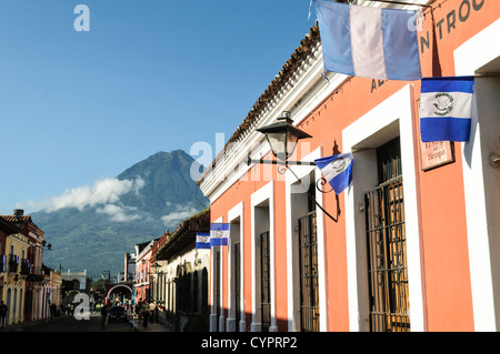 ANTIGUA GUATEMALA, Guatemala — rues pavées d'Antigua Guatemala bordées de bâtiments colorés de l'époque coloniale. Les piétons se promènent devant des façades vibrantes et des portes ornées, tandis que l'emblématique volcan Agua se profile en arrière-plan, incarnant le charme de ce site classé au patrimoine mondial de l'UNESCO. Banque D'Images