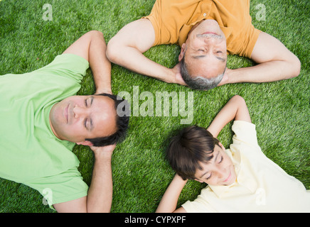 Mother, father and son laying in grass Banque D'Images