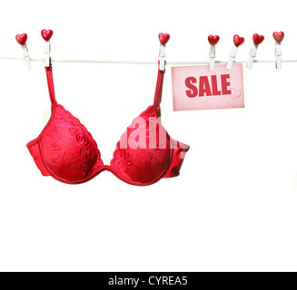 Soutien-gorge rouge fantaisie accroché sur corde avec fond blanc Banque D'Images