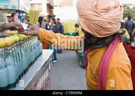 Vendeur de rue l'aumône à un mendiant, New Delhi, Inde Banque D'Images