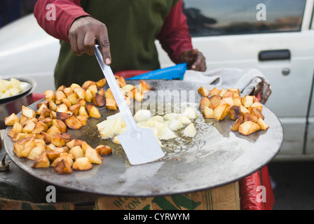Tranches de pommes de terre à frire l'homme sur une crêpière, New Delhi, Inde Banque D'Images
