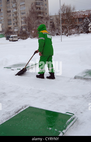 Travailleur avec une pelle efface la neige en hiver Banque D'Images