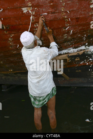 L'homme travaillant sur l'imperméabilité d'un dhow, Al Hodeidah Harbour, au Yémen Banque D'Images