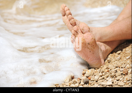 Détente sur la plage, le détail des pieds mâles Banque D'Images