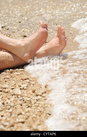 Détente sur la plage, le détail des pieds mâles Banque D'Images