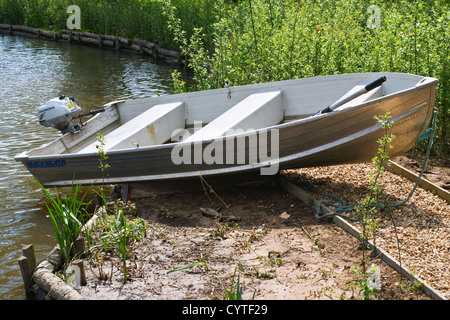 Un petit bateau échoué sur le Quick Silver avec un moteur hors-bord à quatre temps Honda sur l'arrière Banque D'Images