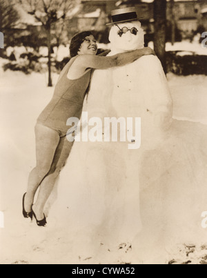 Vintage 1930's press photo of young woman hugging snowman avant d'aller dans l'eau pour nager, Manhattan Beach, New York, États-Unis Banque D'Images