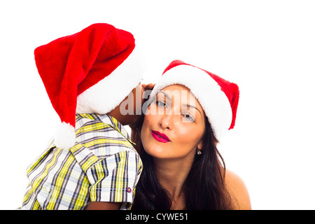 Belle jeune femme et enfant garçon chapeau Noël en chuchotant, isolé sur fond blanc. Banque D'Images