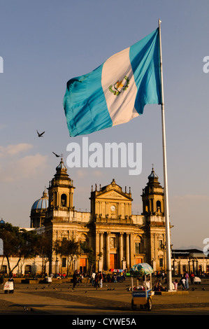 Un grand drapeau du Guatemala sur la place en face de la Catedral Metropolitana (Cathédrale Métropolitaine) sur l'extrémité est du Parque Central (officiellement la Plaza de la Constitución) dans le centre de la ville de Guatemala, Guatemala. Banque D'Images