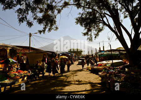 Scène de marché Volcán de Agua Antigua Guatemala // ANTIGUA, Guatemala — Une scène de marché animée se déroule dans la ville coloniale d’Antigua, avec l’imposant Volcán de Agua (volcan d’eau) qui s’élève de façon spectaculaire en arrière-plan. Le stratovolcan dormant de 3 760 mètres (12 340 pieds) fait partie de l'Arc volcanique d'Amérique centrale et sert de toile de fond emblématique à la ville classée au patrimoine mondial de l'UNESCO. Les marchés d'Antigua présentent généralement des textiles colorés, des produits frais et des produits artisanaux d'artisans locaux. L'ancienne capitale du Guatemala est connue pour son architecture baroque espagnole bien conservée et Banque D'Images