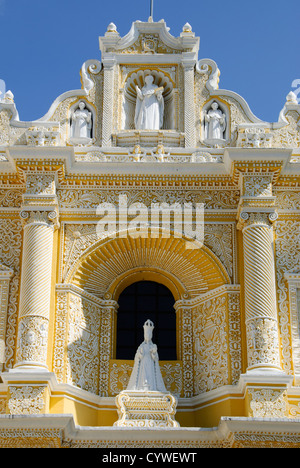 Iglesia de la Merced Exterior Antigua Guatemala // ANTIGUA, Guatemala — statues et décorations sur l'extérieur jaune et blanc distinctif et orné de l'Iglesia y Convento de Nuestra Senora de la Merced dans le centre-ville d'Antigua, Guatemala. La façade baroque présente des stucs complexes, des colonnes tordues et de multiples niches abritant des statues de saints, dont la Vierge Marie au-dessus de l'entrée principale. Banque D'Images