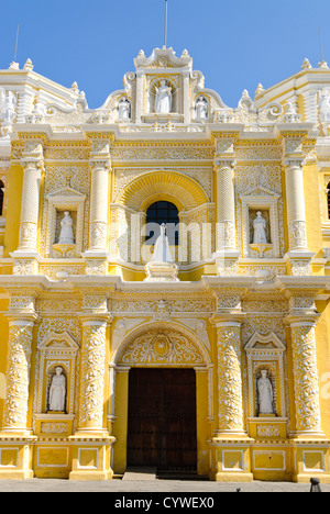 Iglesia de la Merced entrée principale Antigua Guatemala // ANTIGUA, Guatemala — entrée principale de l'extérieur jaune et blanc distinctif et orné de l'Iglesia y Convento de Nuestra Señora de la Merced dans le centre-ville d'Antigua, Guatemala. La façade est richement ornée de stuc blanc complexe, y compris des statues de saints, des colonnes torsadées et des motifs décoratifs, le tout placé contre les murs jaunes vibrants. Banque D'Images
