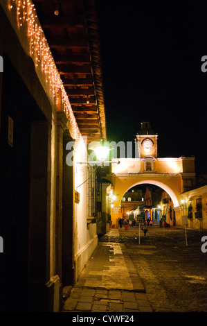 Arche de Santa Catalina Antigua Guatemala / ANTIGUA GUATEMALA, Guatemala — la célèbre Arche de Santa Catalina dans le centre-ville d'Antigua, Guatemala, relie deux parties d'un couvent à travers l'une des principales rues pavées de la ville. Illuminée la nuit, l'arche emblématique est un symbole du patrimoine colonial de la ville, avec sa tour de l'horloge et la rue pavée animée en contrebas. Banque D'Images
