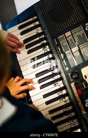 Un garçon à jouer du clavier de piano dans une classe dans une école secondaire, le Pays de Galles UK Banque D'Images