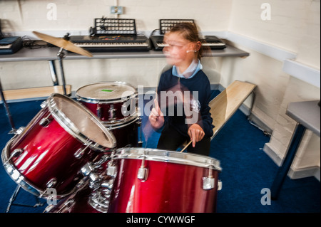 Une fille à jouer de la batterie, dans un cours de musique leçon dans une école secondaire, le Pays de Galles UK Banque D'Images