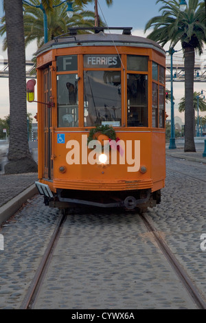 Orange vintage streetcar sur le bord de route (l'Embarcadero) de San Francisco avec des palmiers et de Bay Bridge en arrière-plan Banque D'Images
