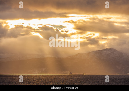 La prise d'un voyage en bateau de minéraux à partir de Narvik, en Norvège. Avec une étrange lumière du soleil ci-dessus. Dans un fjord. Banque D'Images