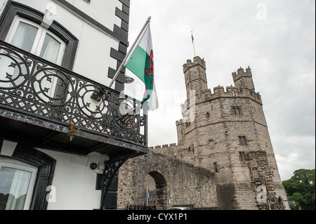 CAERNARFON, Pays de Galles - Un drapeau flotte à partir de la terrasse d'un bâtiment à l'extérieur des murs du château au château de Caernarfon, dans le nord-ouest du pays de Galles. Un château s'élevait à l'origine sur le site remontant à la fin du xie siècle, mais à la fin du 13e siècle, le Roi Edward J'ai commandé une nouvelle structure qui se tient à ce jour. Il possède des tours et est l'un des mieux conservés de la série de châteaux-QUE J'ai commandé. Banque D'Images