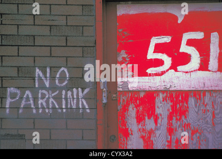 No Parking Sign écrit sur un mur de briques avec adresse en rouge et blanc Banque D'Images