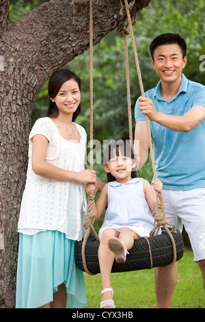 Joyeux famille jouant sur une balançoire en plein air Banque D'Images