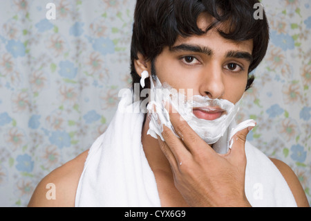 L'homme d'appliquer la crème à raser sur son visage Banque D'Images