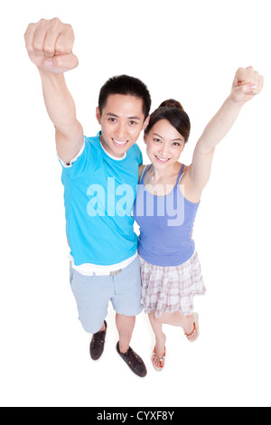 Jeune couple smiling, soulevant les poings dans l'air Banque D'Images