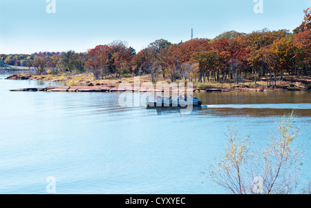 Un bateau ponton avec trois hommes tête à partir d'une anse à Arcadia Lake dans l'Oklahoma, USA, pour une journée de pêche au cours de l'automne. Banque D'Images