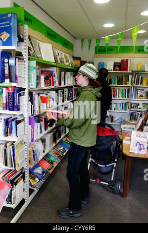 Une jeune femme parcourt les livres dans un magasin de charité Oxfam en Angleterre Banque D'Images