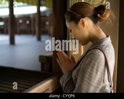 Belle jeune femme japonais visitant Meiji Jingu, Tokyo. Priant au hall principal, shaden, du sanctuaire. Banque D'Images